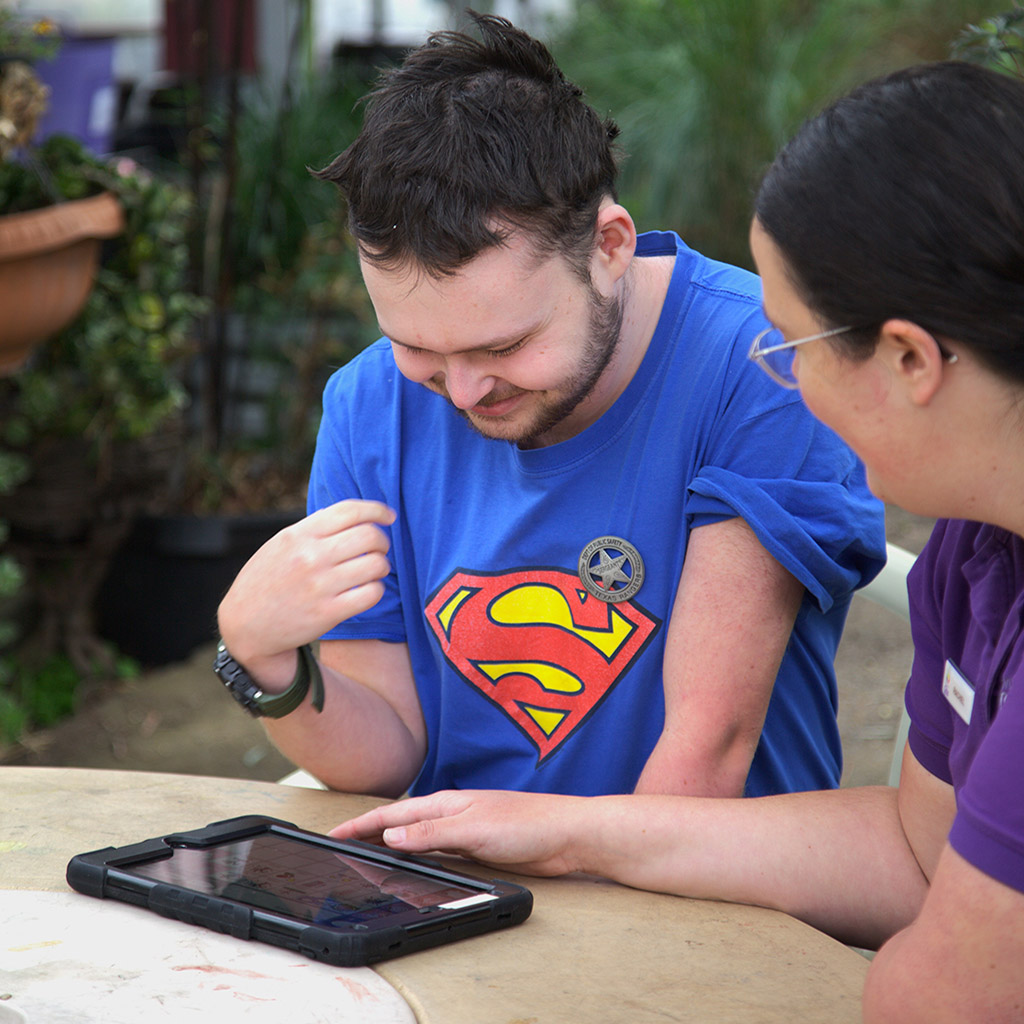 Female speech therapist working with young man on a tablet computer